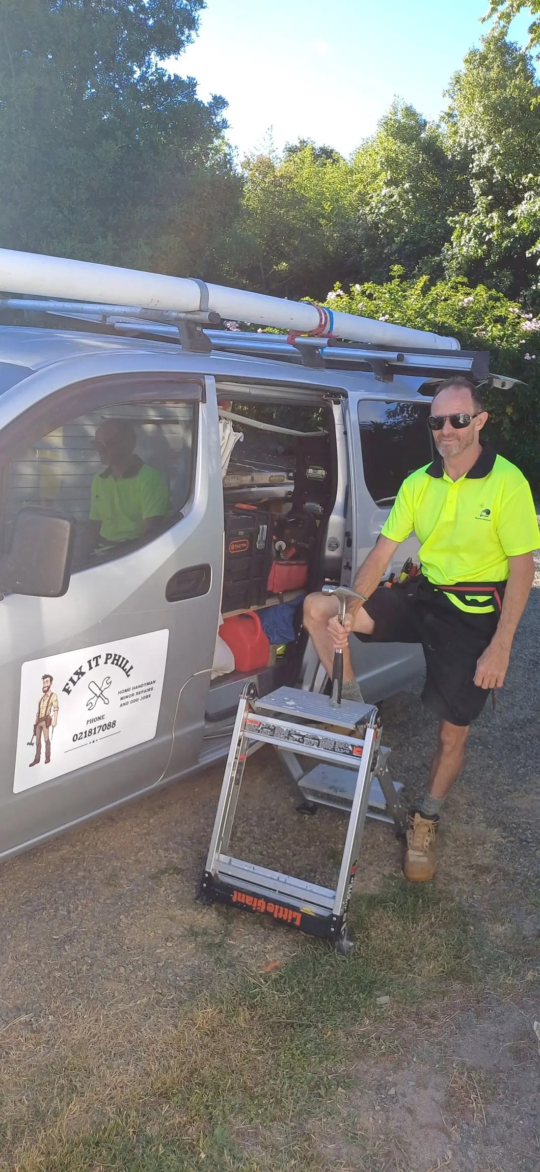 Phill at the open side door of his van, ladder set up, tools inside