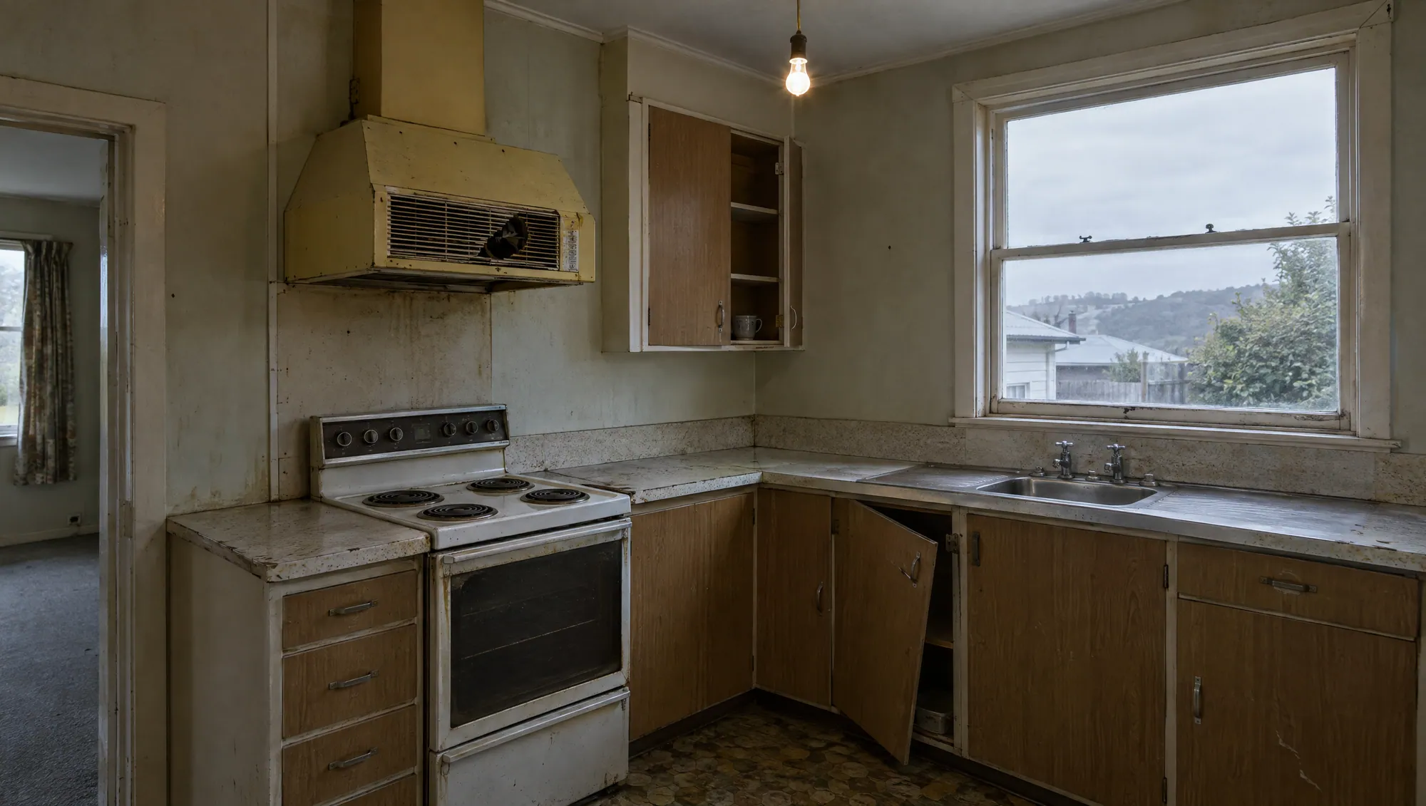 Illustrative dated kitchen: old rangehood, bare bulb, loose cabinet door